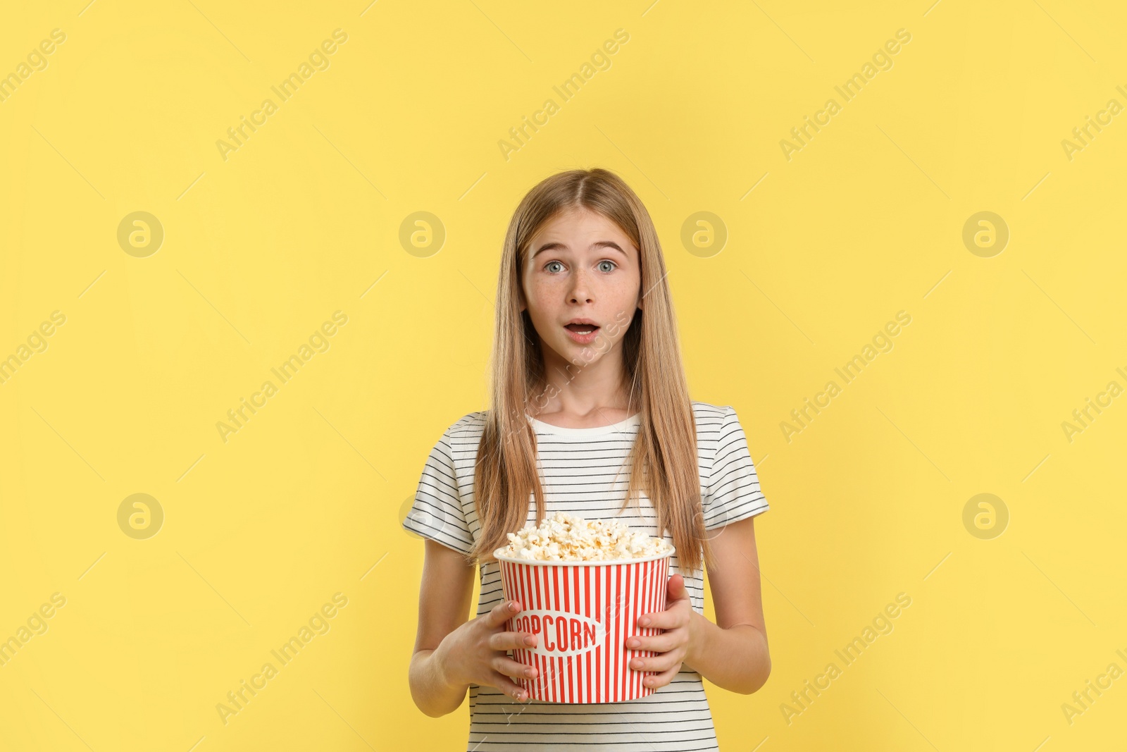 Photo of Emotional teenage girl with popcorn during cinema show on color background