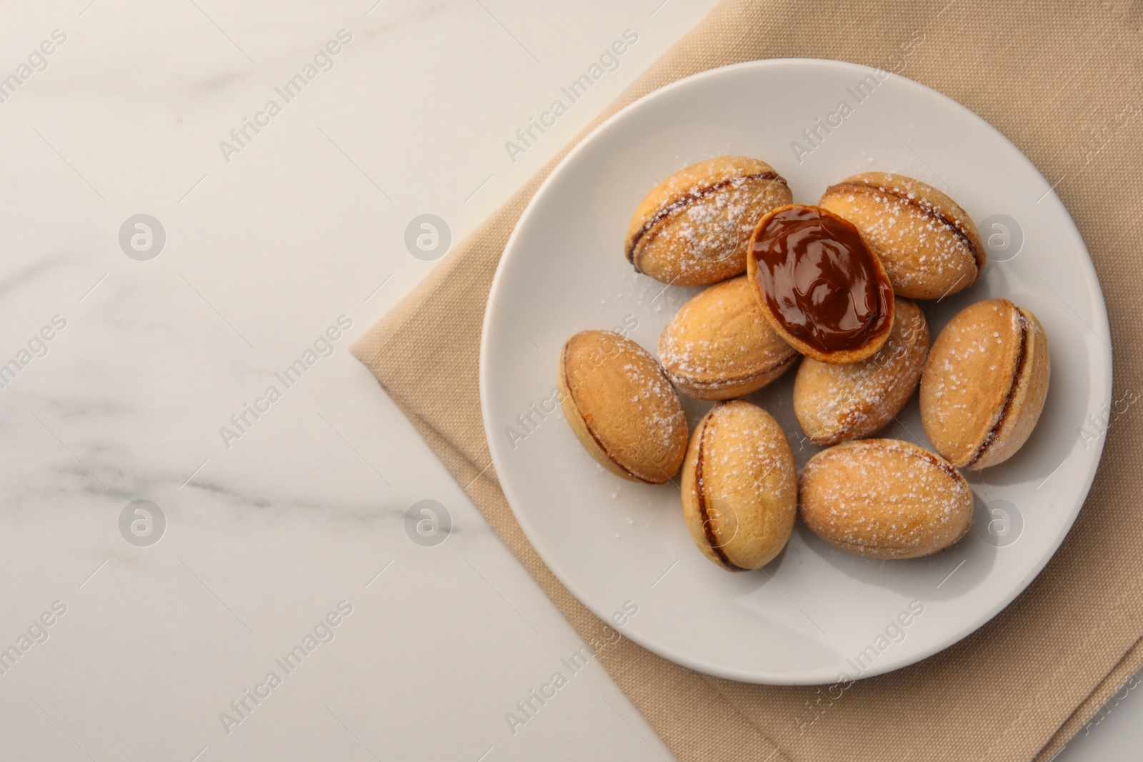 Photo of Homemade walnut shaped cookies with boiled condensed milk on white marble table, top view. Space for text