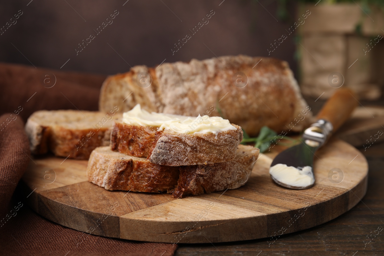Photo of Slices of tasty bread with butter and knife on wooden table, closeup. Space for text