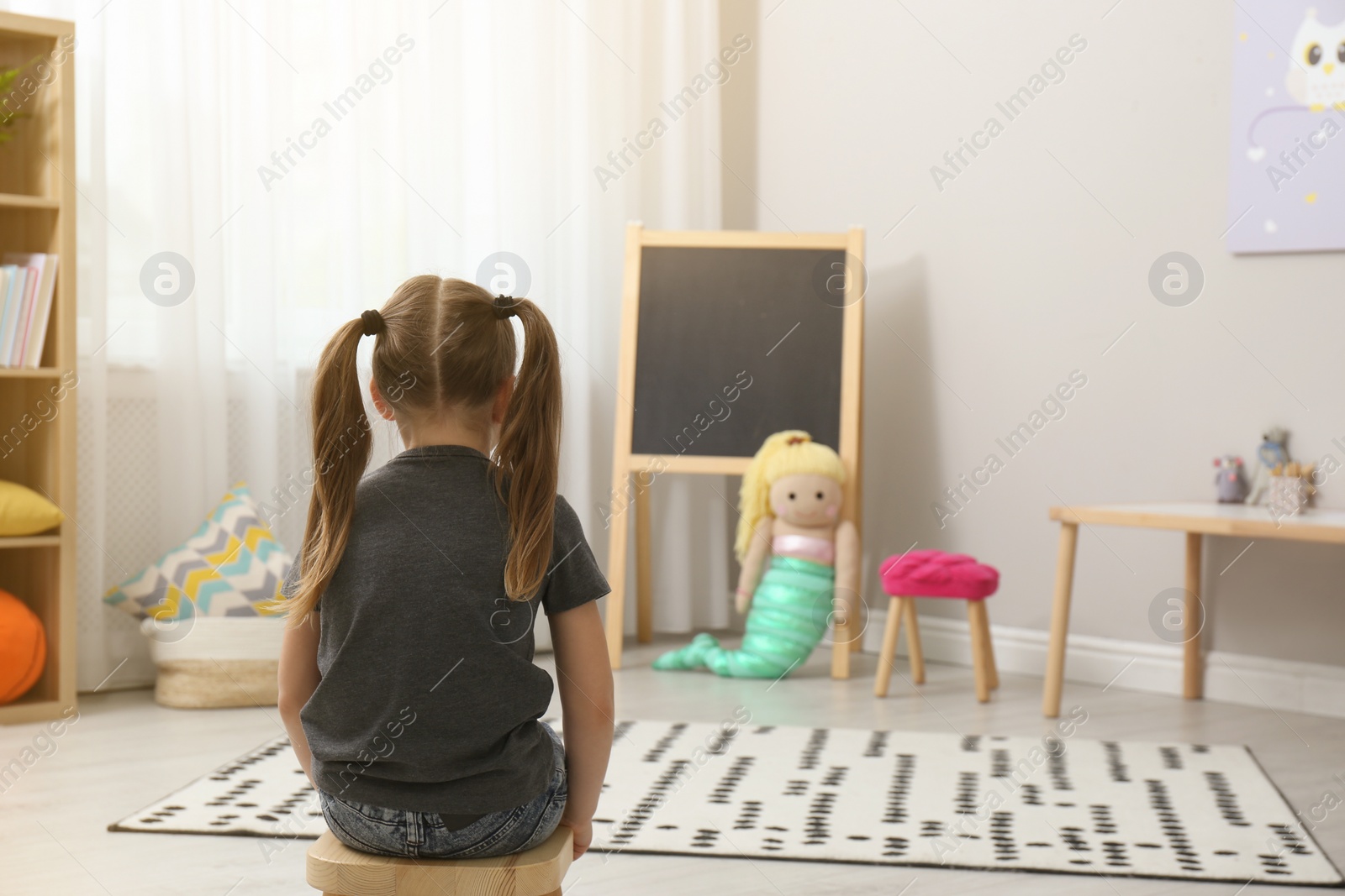 Photo of Lonely little girl at home, back view. Autism concept