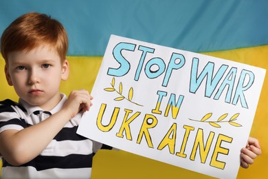 Photo of Boy holding poster Stop War in Ukraine against national flag