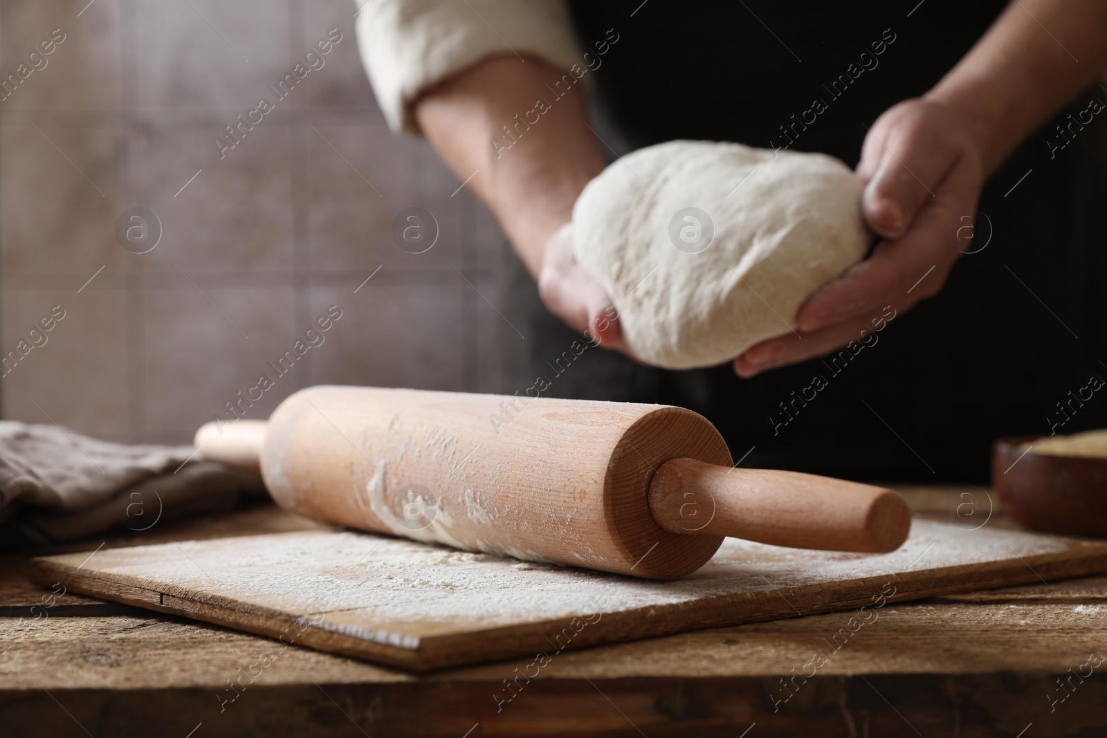 Photo of Man making dough at wooden table, closeup