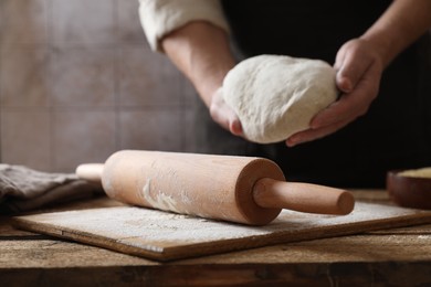 Photo of Man making dough at wooden table, closeup