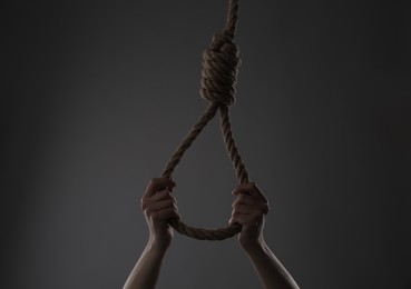 Photo of Woman holding rope noose on grey background, closeup