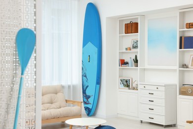 SUP board and modern furniture in stylish living room. Interior design