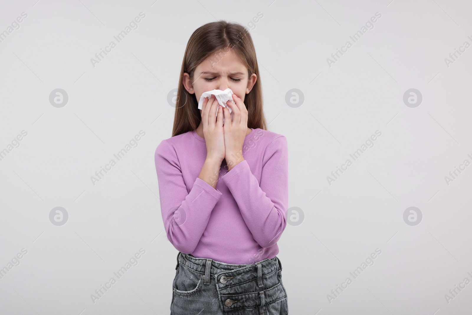 Photo of Sick girl with tissue coughing on light background