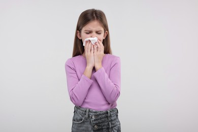 Photo of Sick girl with tissue coughing on light background
