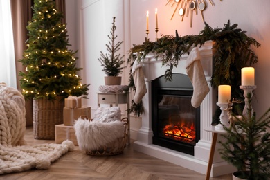 Photo of Stylish room interior with fireplace and beautiful Christmas tree