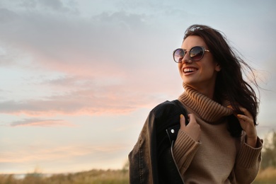 Photo of Beautiful young woman wearing stylish autumn clothes outdoors