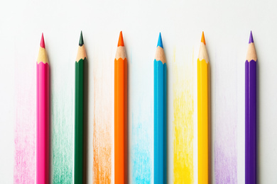 Photo of Colorful pencils with swatches on white background, top view