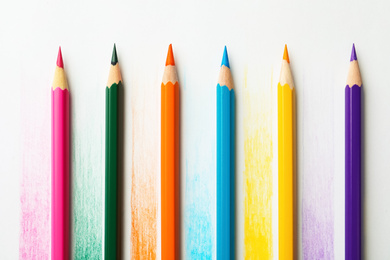 Colorful pencils with swatches on white background, top view