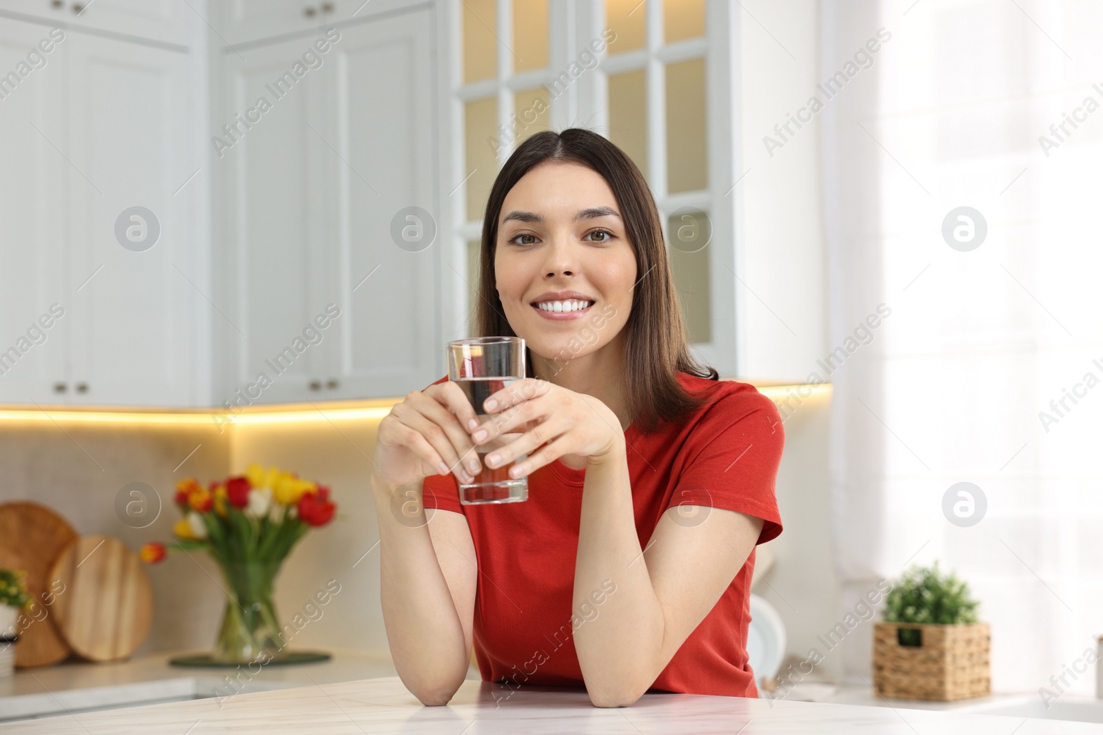 Photo of Young woman with glass of water in kitchen