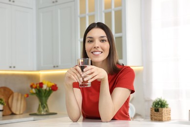 Photo of Young woman with glass of water in kitchen