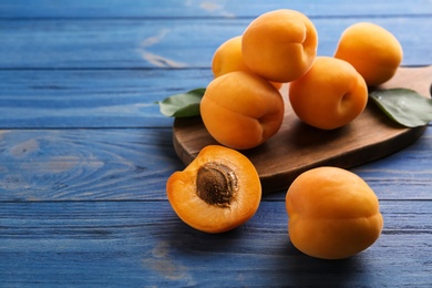 Photo of Composition with delicious apricots on blue wooden background. Space for text