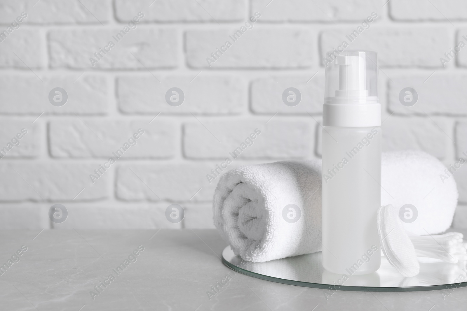 Photo of Bottle of face cleansing product, towel, cotton pads and buds on grey table. Space for text