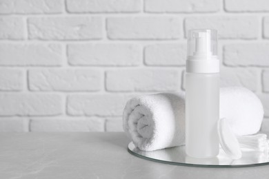 Bottle of face cleansing product, towel, cotton pads and buds on grey table. Space for text