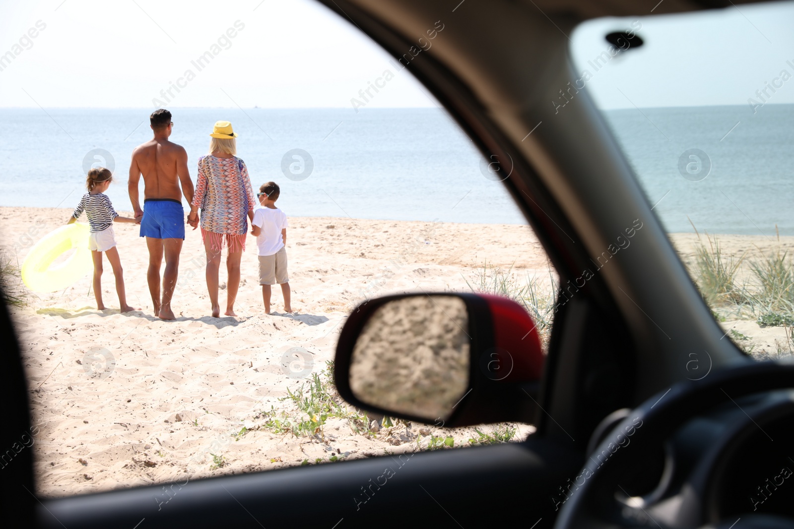 Photo of Family with inflatable ring at beach, view from inside of car