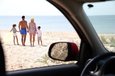 Family with inflatable ring at beach, view from inside of car