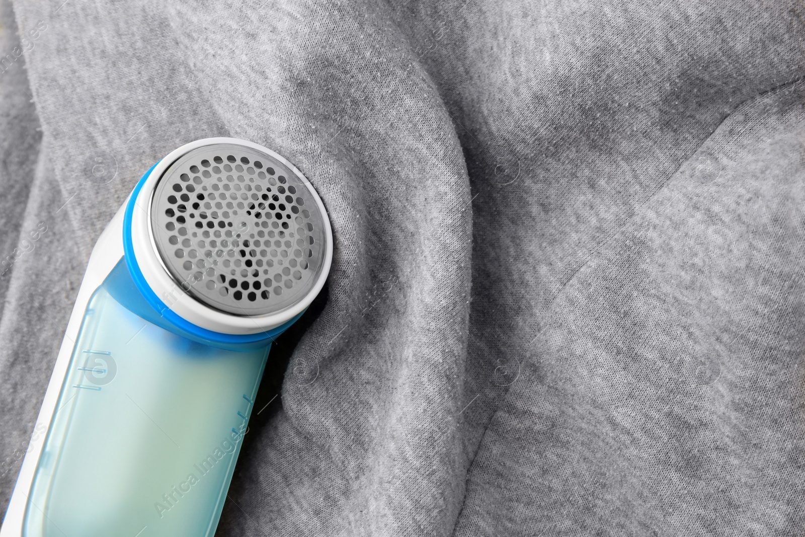 Photo of Modern fabric shaver and light grey cloth with lint on yellow background, above view. Space for text