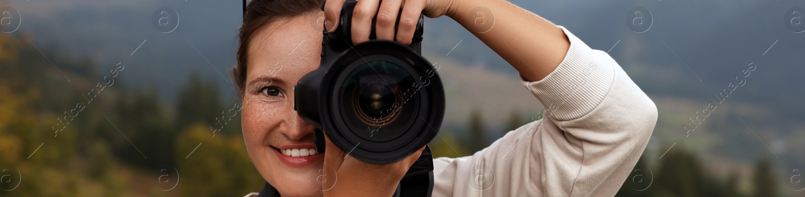 Image of Professional photographer taking picture with modern camera in mountains. Banner design