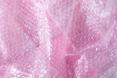 Photo of Transparent bubble wrap on pink background, top view