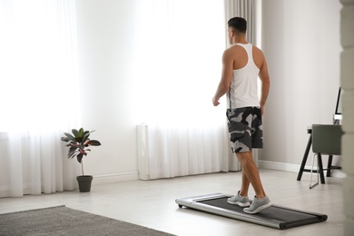 Photo of Sporty man training on walking treadmill at home