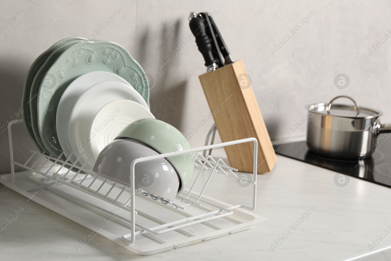 Photo of Drainer with different clean dishware on white table indoors