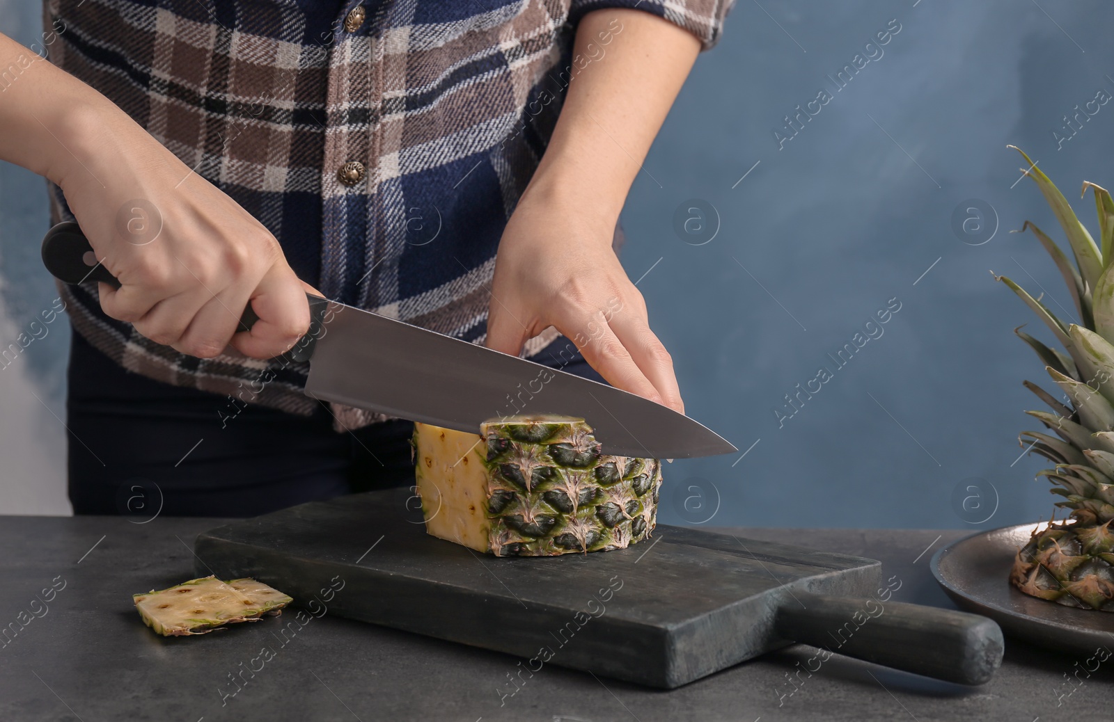 Photo of Woman cutting fresh pineapple on wooden board