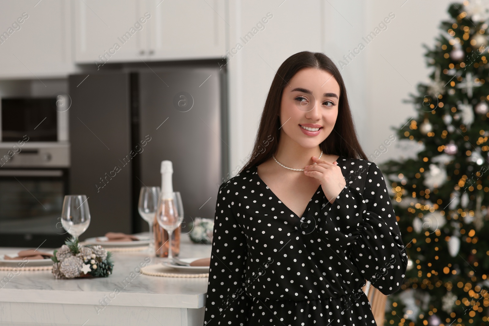 Photo of Happy woman near table served for Christmas in kitchen