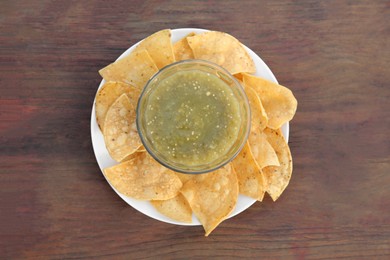 Tasty salsa sauce and tortilla chips on wooden table, top view