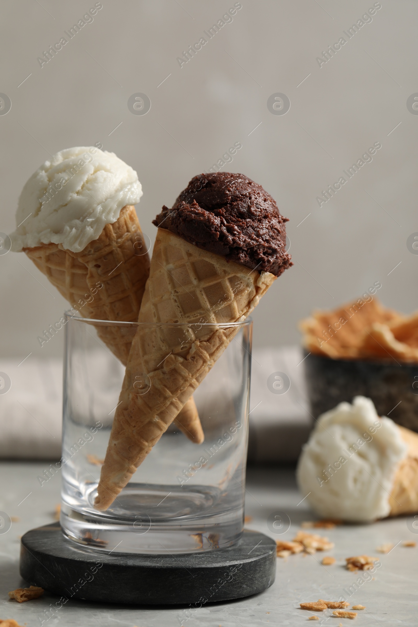 Photo of Tasty ice cream scoops in waffle cones on grey marble table, closeup