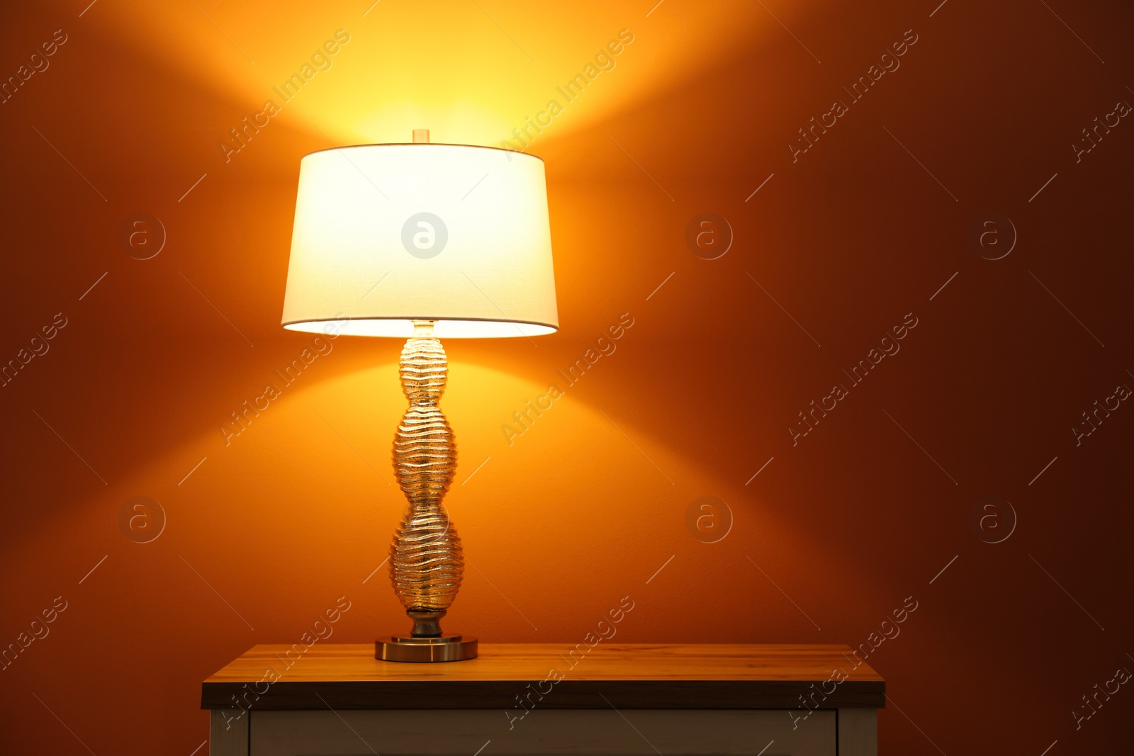 Photo of Stylish glowing  night lamp on table in room. Space for text
