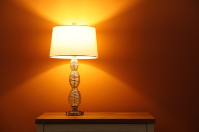 Stylish glowing  night lamp on table in room. Space for text