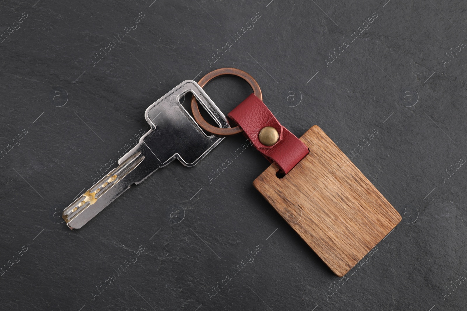 Photo of Key and wooden keychain with Ukrainian coat of arms on grey background, top view