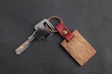 Key and wooden keychain with Ukrainian coat of arms on grey background, top view