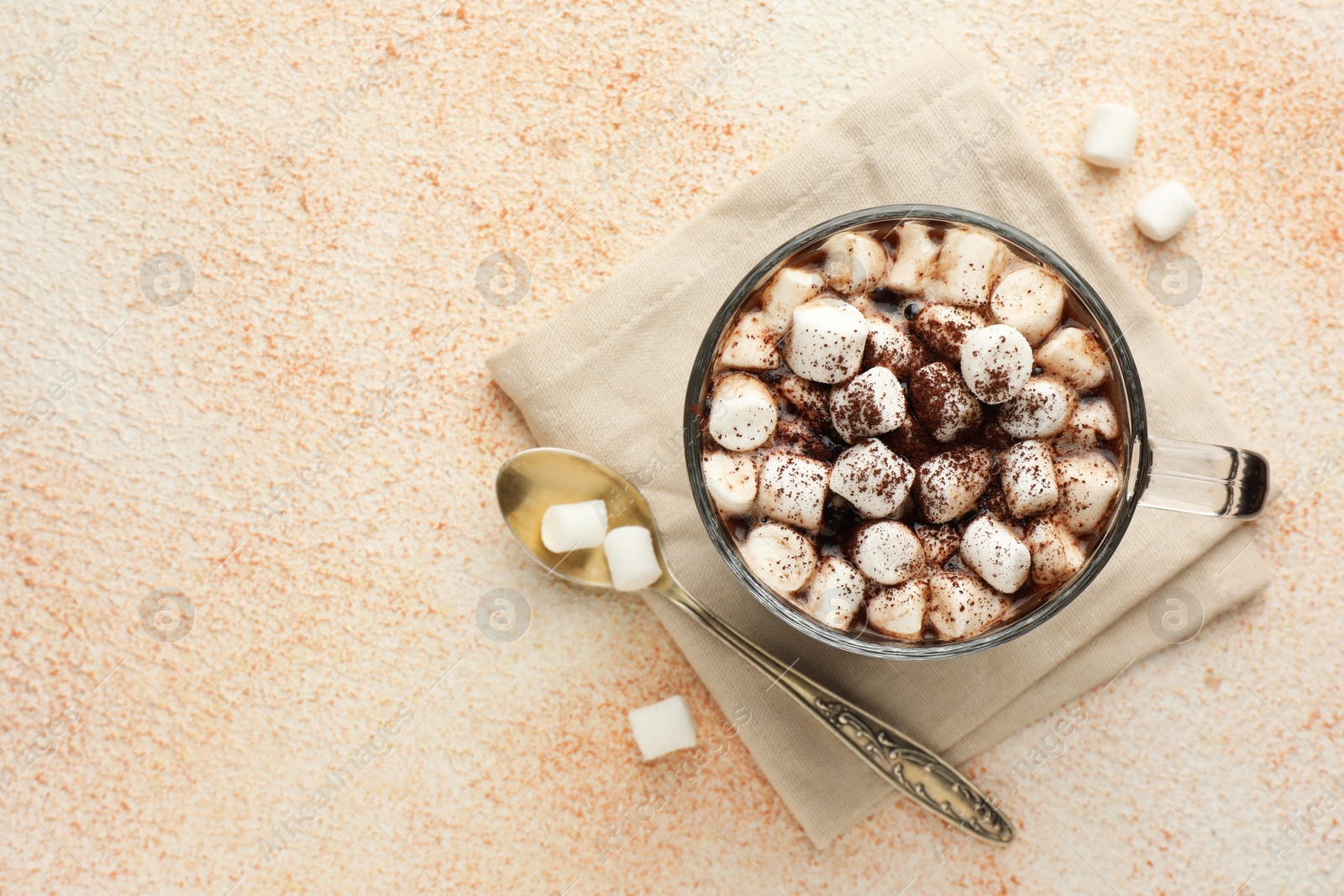 Photo of Cup of aromatic hot chocolate with marshmallows and cocoa powder served on beige table, flat lay. Space for text