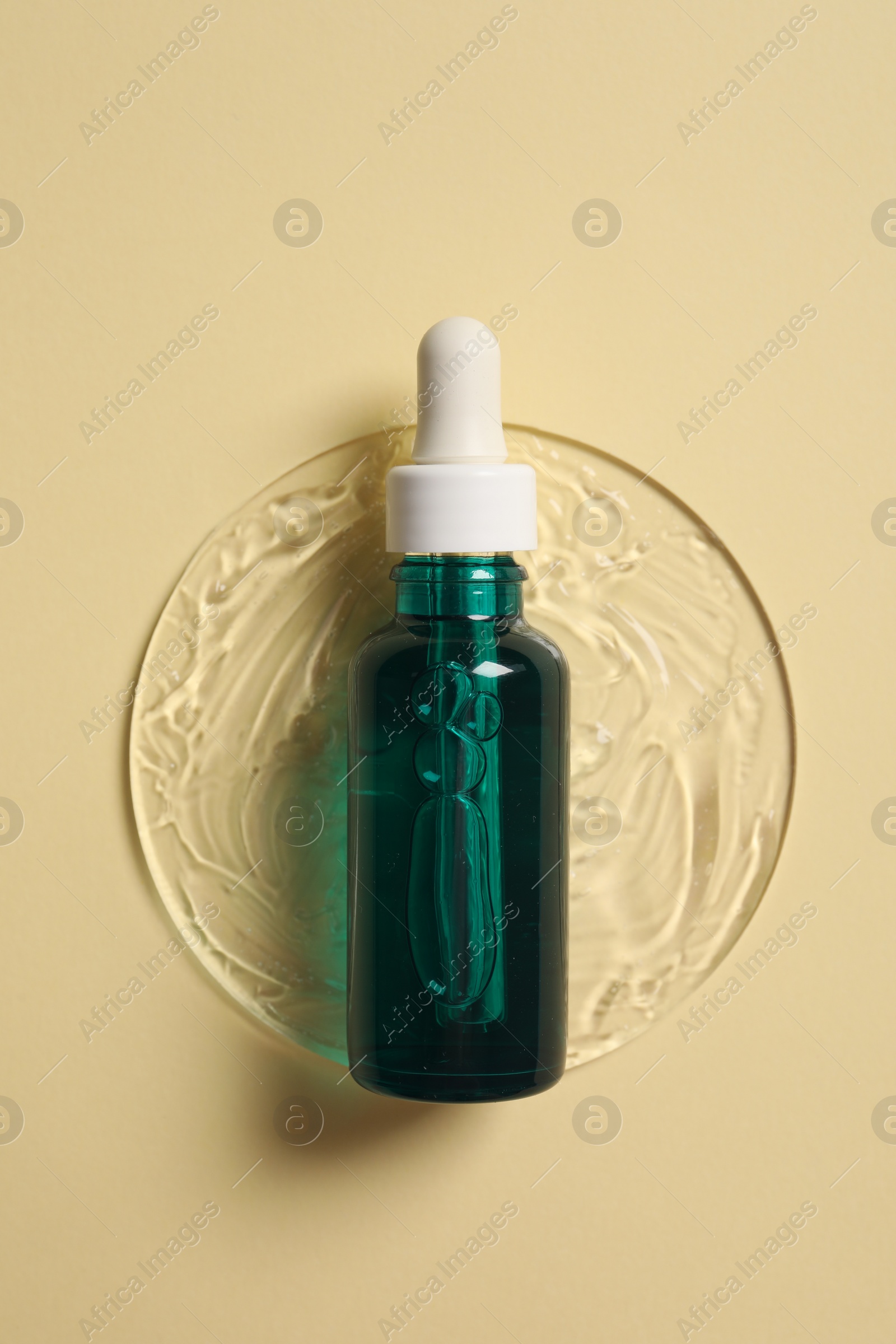 Photo of Bottle of cosmetic serum on beige background, top view