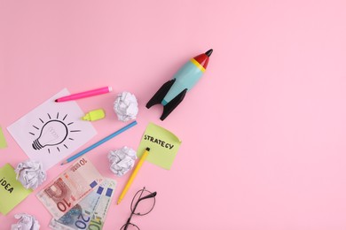 Photo of Flat lay composition with stationery, money and toy rocket on pink background, space for text. Startup concept