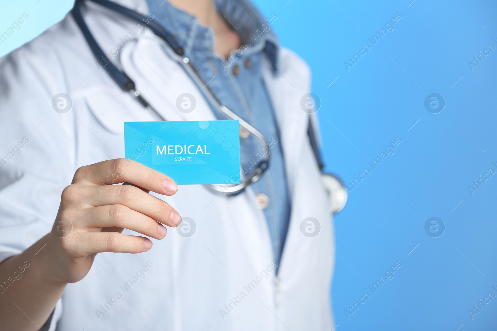 Photo of Doctor holding business card on color background, closeup with space for text. Medical service