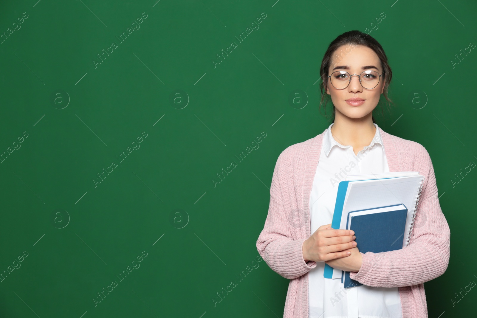 Photo of Portrait of beautiful young teacher with books near chalkboard, space for text