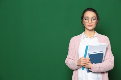 Portrait of beautiful young teacher with books near chalkboard, space for text