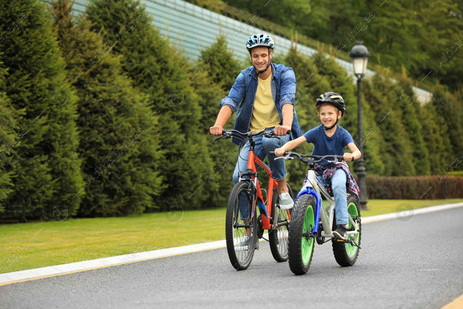 Photo of Dad and son riding modern bicycles outdoors