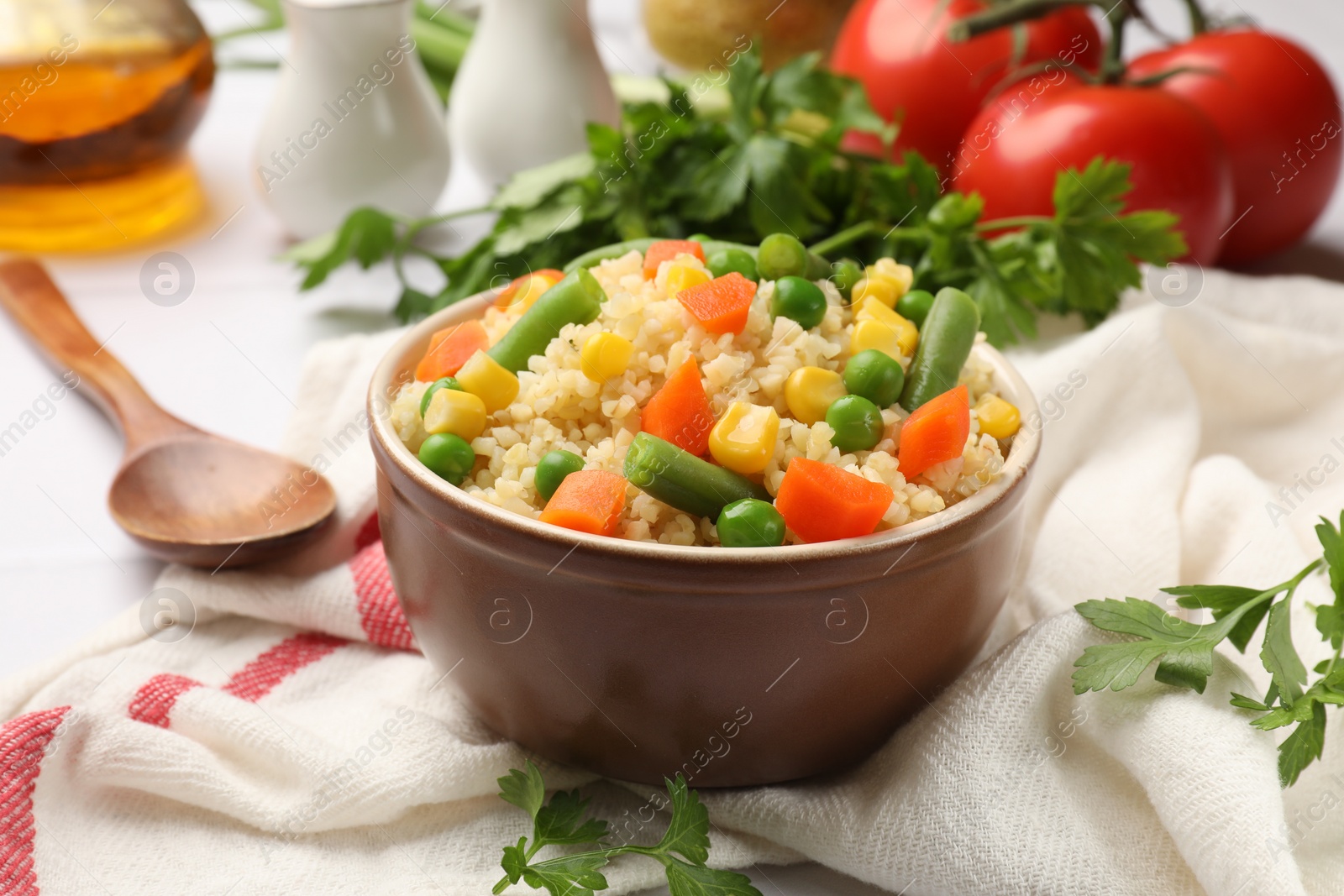 Photo of Delicious bulgur with vegetables in bowl served on table, closeup