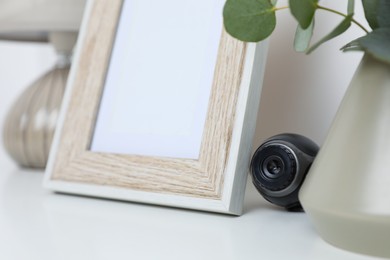 Photo of Small camera hidden among home stuff on white table