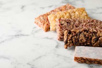 Photo of Tasty protein bars on marble table. Space for text