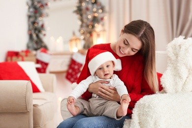 Photo of Happy mother with cute baby in room decorated for Christmas holiday