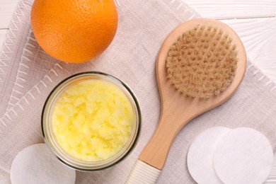 Natural body scrub, orange, brush and cotton pads on white wooden table, flat lay. Anti cellulite treatment