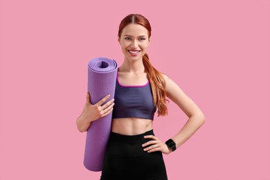 Photo of Woman in sportswear with fitness mat on pink background