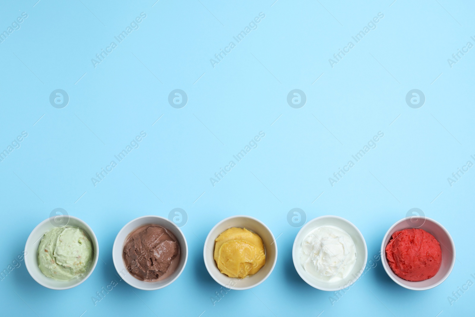 Photo of Different delicious ice creams on light blue background, flat lay. Space for text