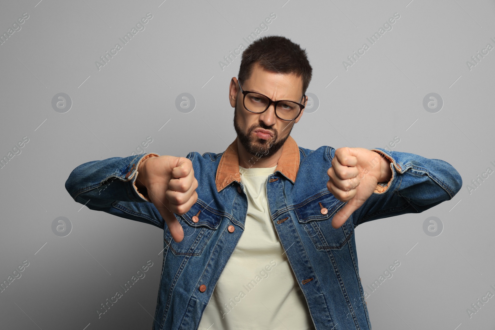 Photo of Man showing thumbs down on grey background